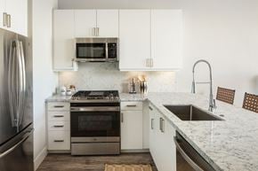Houston apartment for rent - A modern kitchen with a stainless steel refrigerator, microwave, oven, and sink.