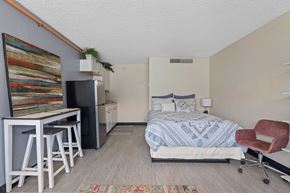 Mesa apartment for rent - A bedroom with a bed, chair, and a fridge.
