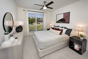 Atlanta apartment for rent - A bedroom with a large bed, a mirror, and a ceiling fan.