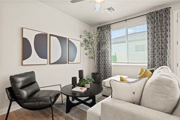 Tolleson apartment for rent - A living room with a black chair, a white couch, and a small table with a plant on it.