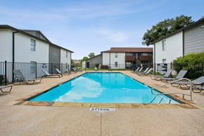 Stephenville apartment for rent - A swimming pool surrounded by chairs and apartment buildings.