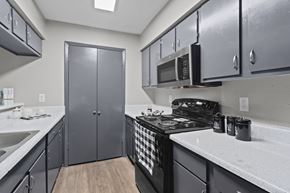 Dallas apartment for rent - A kitchen with a black stove top oven and a black microwave above it.