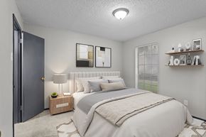 Dallas apartment for rent - A bedroom with a large bed and a nightstand with a lamp.