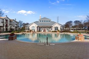 Waco apartment for rent - A large swimming pool in front of a building with a fountain in the middle.
