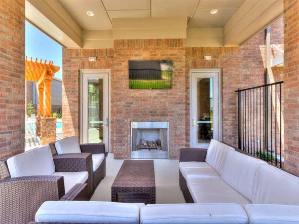 Oklahoma City apartment for rent - A patio with a white couch, brown wicker chairs, and a fireplace.