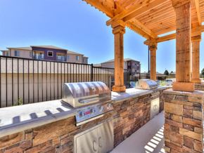 Oklahoma City apartment for rent - A BBQ grill is on a patio with a stone wall and a wooden pergola.