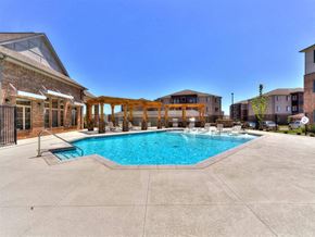 Oklahoma City apartment for rent - A large swimming pool surrounded by a concrete patio and a wooden pergola.
