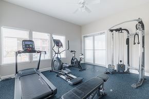 Pearland apartment for rent - A spacious home gym with a treadmill, elliptical trainer, and other exercise equipment.