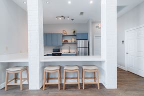 Pearland apartment for rent - A kitchen with white walls and a white counter top with three stools.