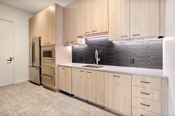 Chicago apartment for rent - A kitchen with wooden cabinets and a black tile backsplash.