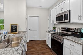 Pooler apartment for rent - A kitchen with white cabinets and a black fridge.