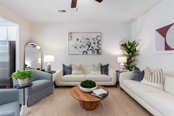 Goose Creek townhouse for rent - A living room with a white couch, a grey armchair, a wooden coffee table, and a painting on the wall.