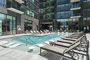 Atlanta apartment for rent - A large indoor swimming pool with lounge chairs and a modern building in the background.