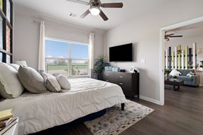 Pflugerville apartment for rent - A bedroom with a large bed and a flat screen TV mounted on the wall.