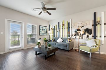 Pflugerville apartment for rent - A living room with a grey couch, a coffee table, a yellow chair, and a painting on the wall.
