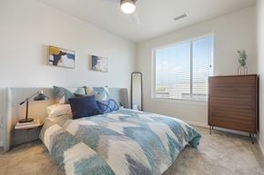 Aurora apartment for rent - A bedroom with a bed, nightstand, and a lamp.