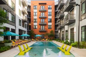 Austin apartment for rent - A pool surrounded by yellow chairs and buildings.