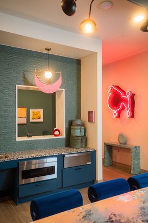 Austin apartment for rent - A modern kitchen with blue chairs and a red neon sign on the wall.