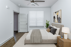 Charlotte apartment for rent - A bedroom with a bed, nightstand, and a ceiling fan.