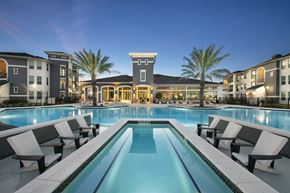 Humble apartment for rent - A swimming pool surrounded by lounge chairs in front of a building.