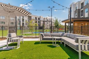 Katy apartment for rent - a lounge area with couches and chairs on a lawn with an apartment building in the background
