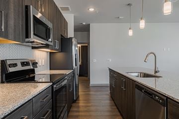 Katy apartment for rent - A modern kitchen with dark wood cabinets and stainless steel appliances.
