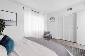 North Miami Beach apartment for rent - A modern bedroom with a large bed and a grey armchair.