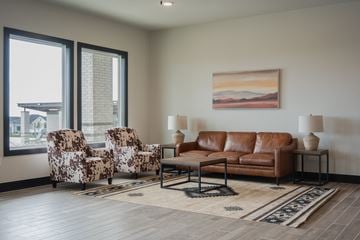 Cresson apartment for rent - A living room with a brown leather couch, two patterned chairs, and a painting on the wall.