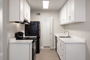 Auburn apartment for rent - A kitchen with white cabinets and a black refrigerator.