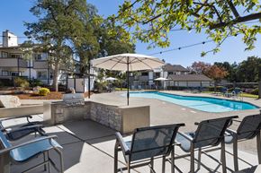 Rocklin apartment for rent - A pool surrounded by chairs and umbrellas with a house in the background.