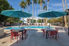 Yuma apartment for rent - A poolside area with tables and chairs and umbrellas.