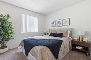 Yuma apartment for rent - A bedroom with a bed, nightstand, and a plant.