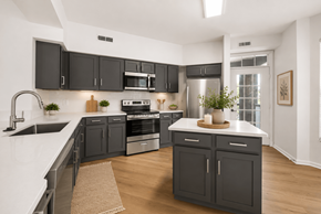 Cincinnati apartment for rent - A modern kitchen with dark grey cabinets and white countertops.