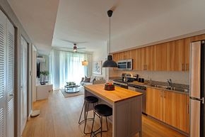 Houston apartment for rent - a kitchen with wooden cabinets and a island with three stools