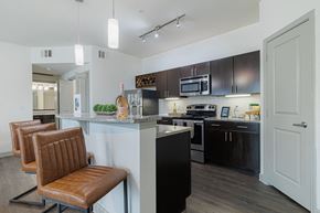 Spring apartment for rent - a kitchen with black and white appliances and a counter with chairs