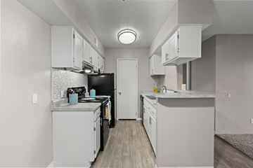 Tucson apartment for rent - A kitchen with white cabinets and a black refrigerator.