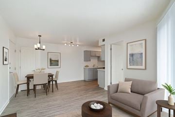 Dallas apartment for rent - A living room with a grey couch, a brown coffee table, and a dining table with chairs.