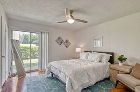 Austin apartment for rent - Bedroom with brown concrete floors, white walls, a ceiling fanand sliding glass doors to a balcony