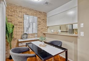 Austin apartment for rent - Small dining area outside a kitchen bartop with midcentury modern brick walls and brown concrete flooring