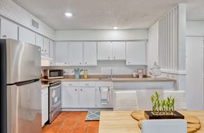 Austin apartment for rent - Kitchen with glossy brown concrete floors, white cabinetry, and stainless steel appliances