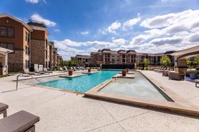Grand Prairie apartment for rent - A large outdoor swimming pool with a hot tub in the middle of a residential area.