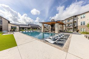 Austin apartment for rent - A large outdoor swimming pool with loungers and a building in the background.