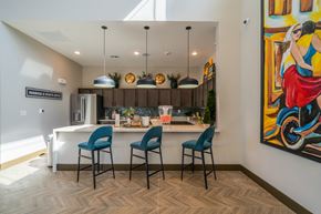 Conroe apartment for rent - a kitchen and dining area with blue chairs and a colorful painting on the wall