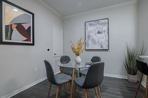 Houston apartment for rent - a dining room with a round table with four chairs and a vase with yellow flowers on