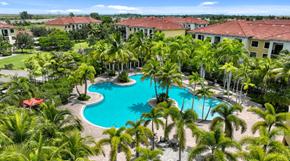 Sunrise apartment for rent - A swimming pool surrounded by palm trees and a resort.