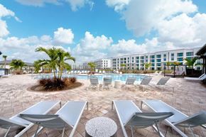 Cape Coral apartment for rent - A pool surrounded by chairs and palm trees.