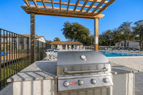 Brandon apartment for rent - A BBQ grill is on a concrete slab with a pergola above it.