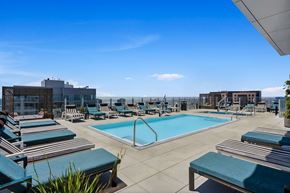 San Diego apartment for rent - A large swimming pool with lounge chairs and a building in the background.
