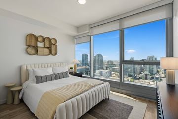 San Diego apartment for rent - A bedroom with a large bed and a city view through the window.