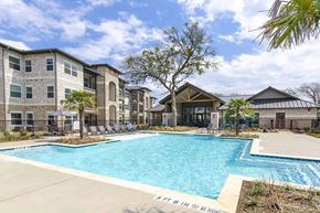 Granbury apartment for rent - A swimming pool in front of apartment buildings with a sign that says